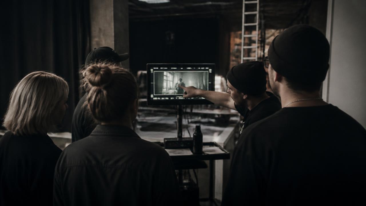 A production team gathered around a monitor cart on set